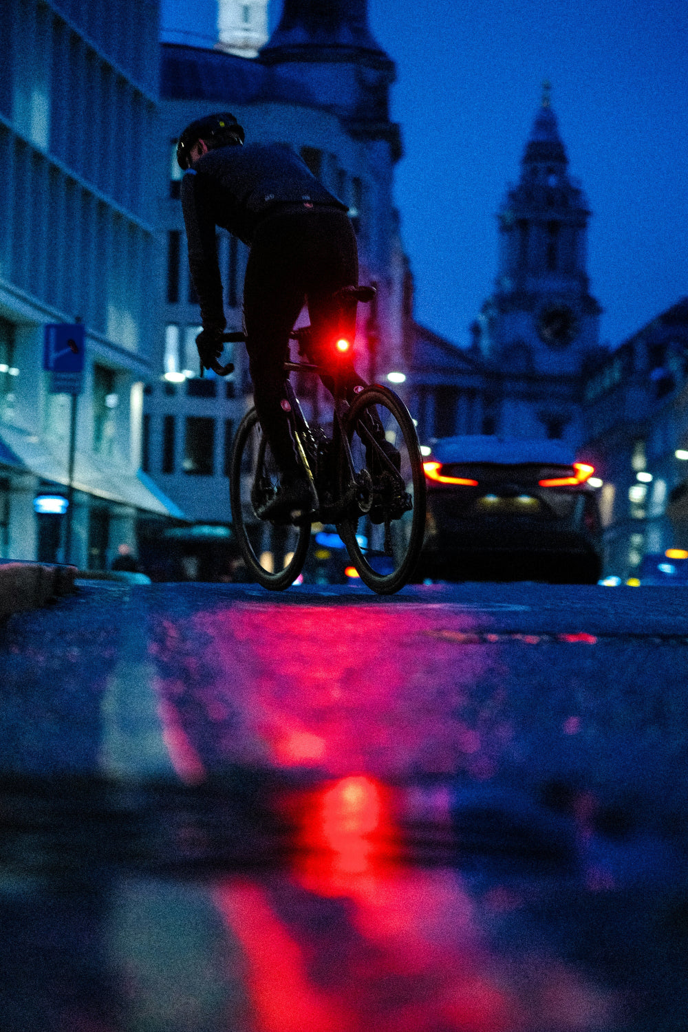 Person riding a bicycle at night with cityscape in the background